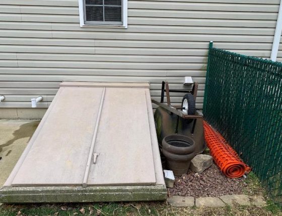 entrance to basement sitting to wheelbarrow and green fence