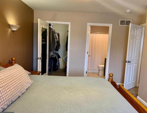 queen size bed sitting parallel to walk in closest and bathroom