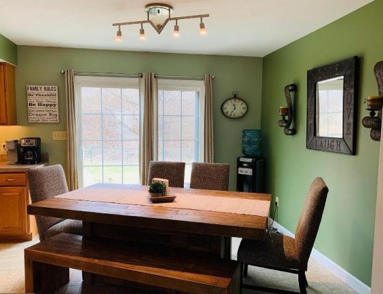 wood dining room table surrounded by green walls and sliding glass door in new home for sale