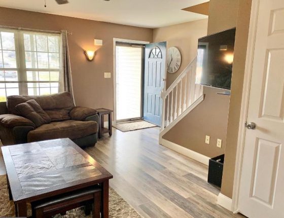 living room furniture sitting on hardwood floor next to open front door