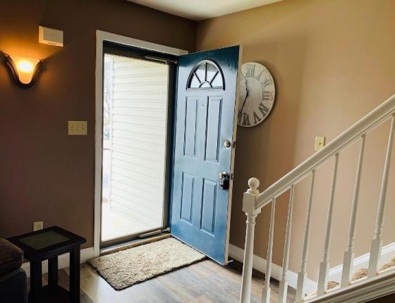 open front door partially blocking view of decorative clock