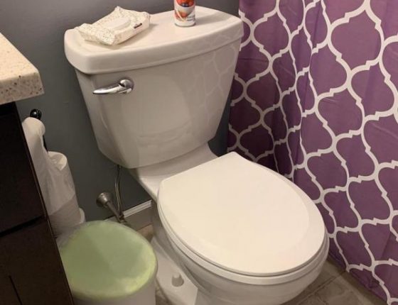 white toilet and trashcan in full bathroom