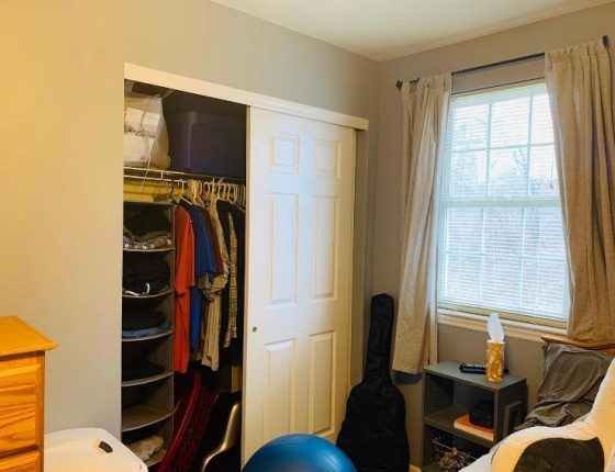 upstairs closet filled with clothes next to guitar case and window